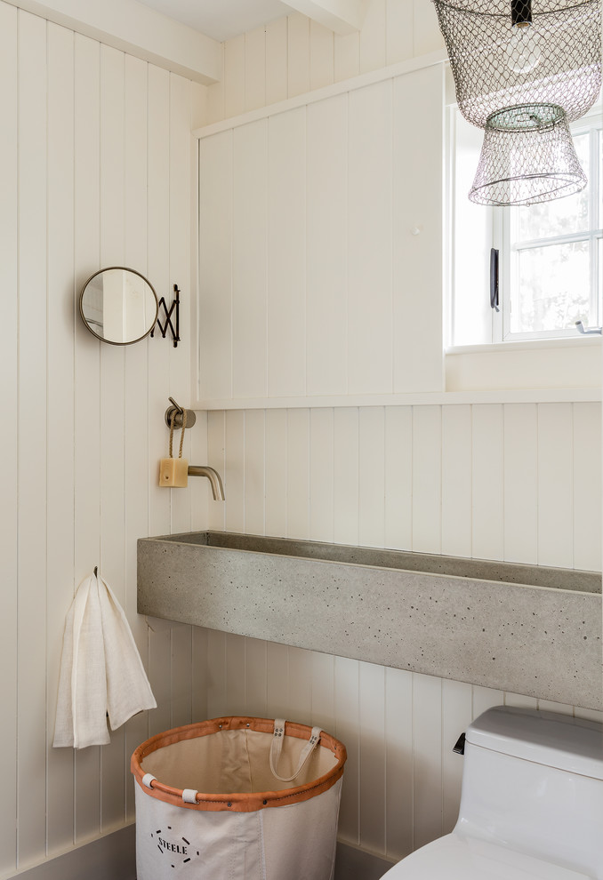 Klassisk inredning av ett badrum, med vita väggar, marmorgolv, ett väggmonterat handfat, bänkskiva i betong och blått golv