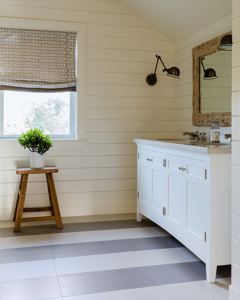 Cette photo montre une salle de bain chic pour enfant avec un placard à porte affleurante, des portes de placard blanches, un carrelage blanc, un mur blanc, un sol en carrelage de céramique, un lavabo encastré, un plan de toilette en béton et un sol multicolore.