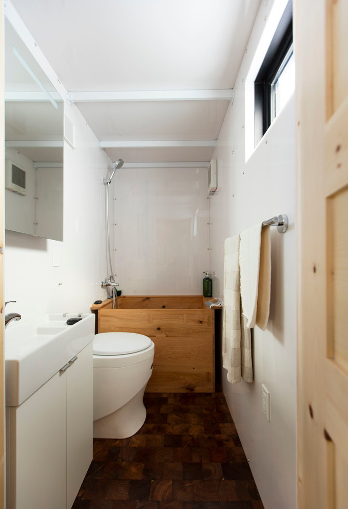 Bathroom - small contemporary master white tile dark wood floor and brown floor bathroom idea in Albuquerque with white walls, flat-panel cabinets, white cabinets and an integrated sink