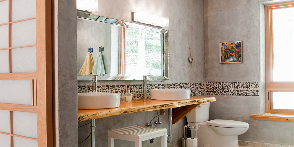 Foto på ett mellanstort rustikt en-suite badrum, med ett fristående badkar, en hörndusch, en toalettstol med separat cisternkåpa, svart kakel, grå kakel, cementkakel, grå väggar, ett fristående handfat, träbänkskiva och dusch med gångjärnsdörr