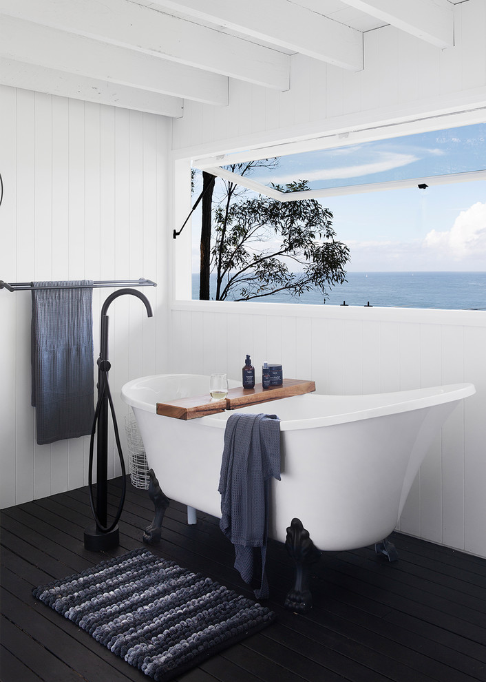 Maritimes Badezimmer mit Löwenfuß-Badewanne, weißer Wandfarbe, gebeiztem Holzboden und schwarzem Boden in Sunshine Coast