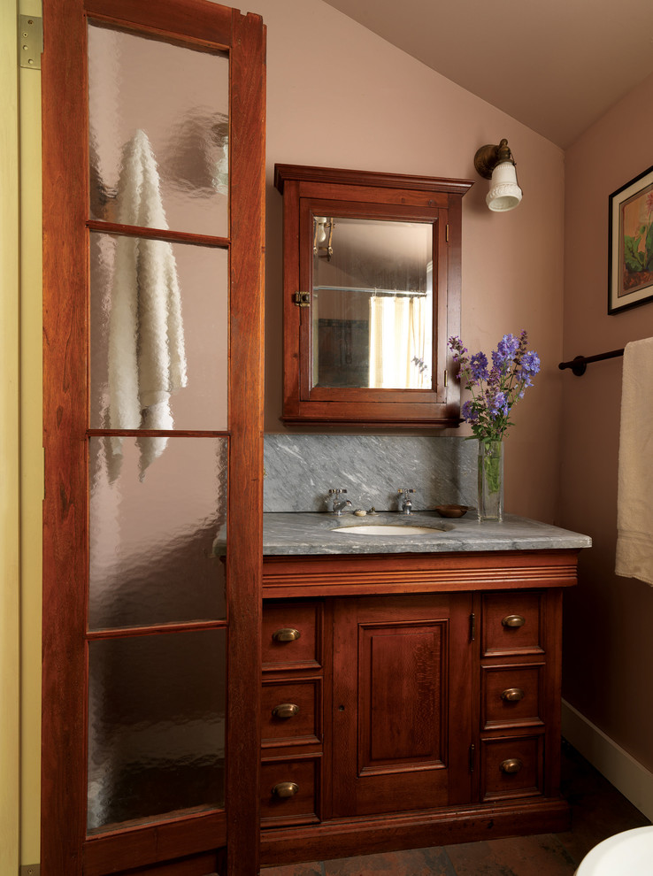 Foto de cuarto de baño rectangular tradicional con lavabo bajoencimera, armarios con paneles empotrados y puertas de armario de madera en tonos medios
