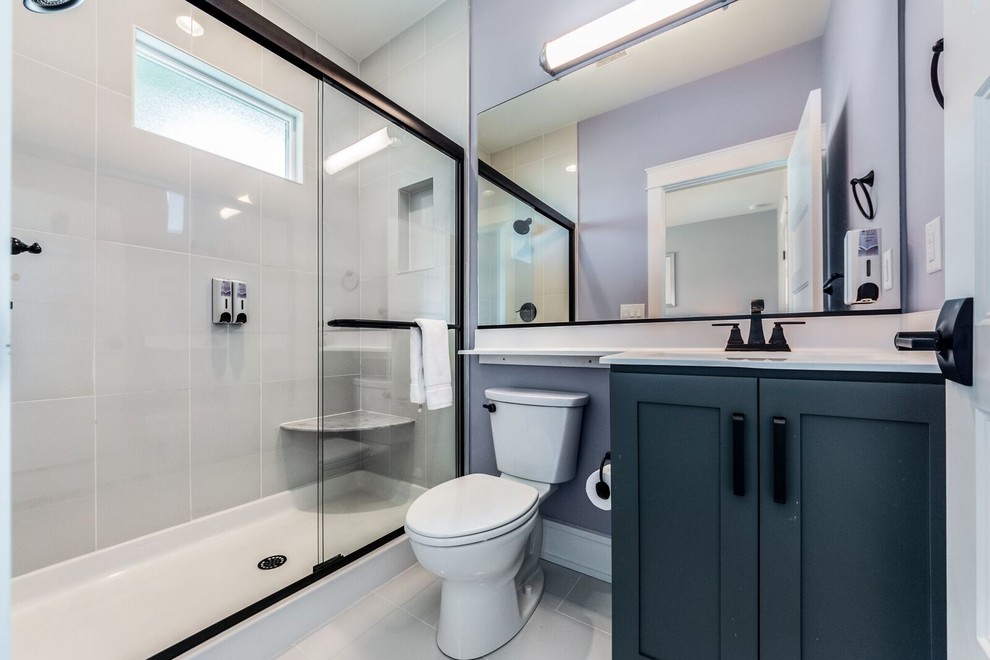 Idéer för att renovera ett mellanstort vintage badrum med dusch, med skåp i shakerstil, grå skåp, en dusch i en alkov, en toalettstol med separat cisternkåpa, grå kakel, porslinskakel, lila väggar, klinkergolv i porslin, ett integrerad handfat, bänkskiva i akrylsten, grått golv och dusch med skjutdörr