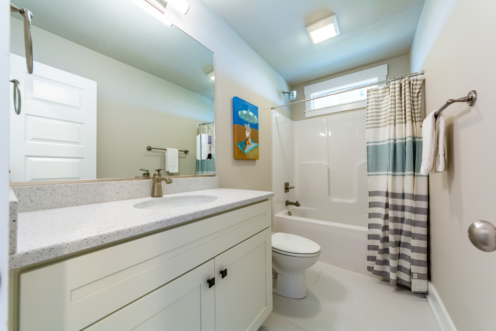 Bild på ett maritimt grå grått en-suite badrum, med luckor med profilerade fronter, grå skåp, ett platsbyggt badkar, en dusch/badkar-kombination, en toalettstol med separat cisternkåpa, beige väggar, klinkergolv i keramik, ett undermonterad handfat, bänkskiva i kvartsit, vitt golv och dusch med duschdraperi