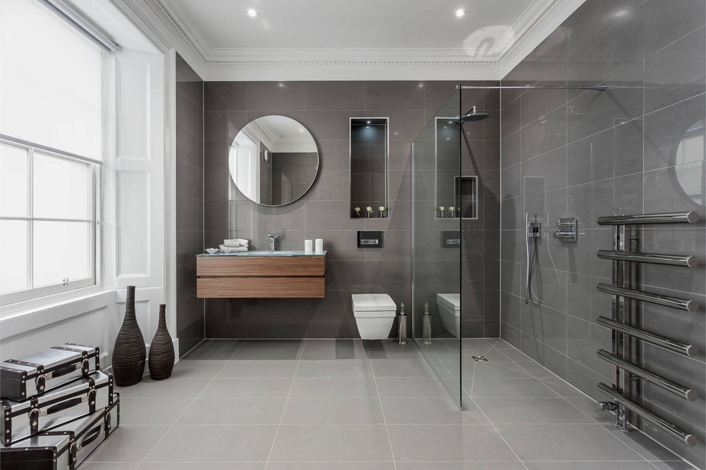 Modern inredning av ett mellanstort en-suite badrum, med en öppen dusch, grå kakel, stenkakel, grå väggar, skiffergolv, bänkskiva i glas, släta luckor, skåp i mörkt trä och med dusch som är öppen