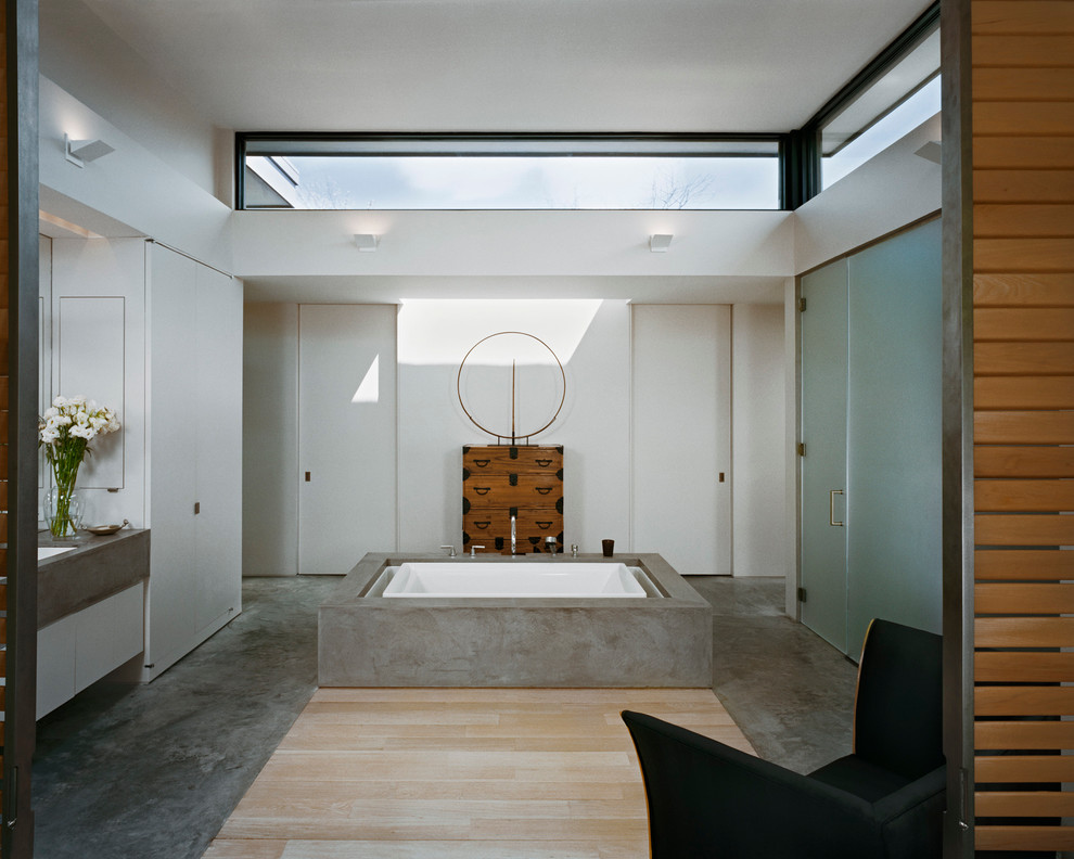 Стильный дизайн: большая главная ванная комната в стиле модернизм с отдельно стоящей ванной, душем в нише, бетонным полом, плоскими фасадами, белыми фасадами, белыми стенами, врезной раковиной, столешницей из бетона, серым полом и душем с распашными дверями - последний тренд