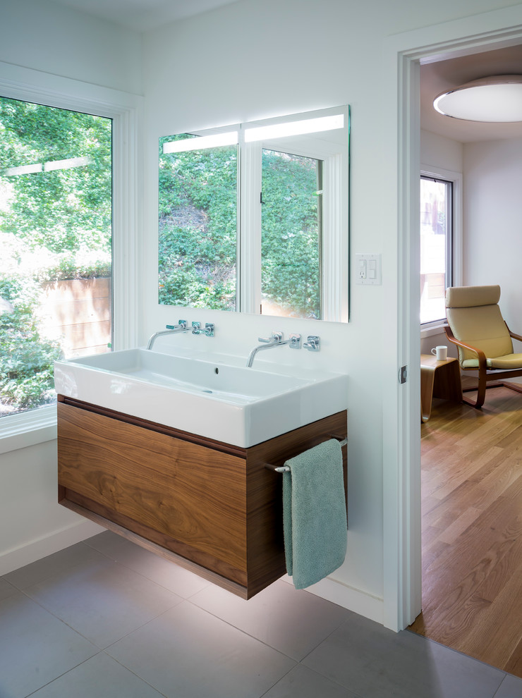 Réalisation d'une salle de bain principale design en bois foncé de taille moyenne avec des carreaux de porcelaine, une grande vasque, un placard à porte plane, un mur blanc et un sol en carrelage de porcelaine.