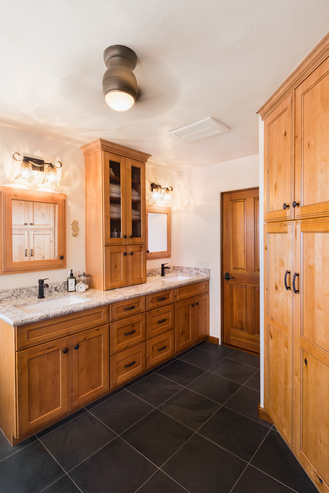 На фото: большая главная ванная комната в стиле кантри с фасадами с утопленной филенкой, коричневыми фасадами, душевой комнатой, унитазом-моноблоком, серой плиткой, керамической плиткой, бежевыми стенами, полом из сланца, врезной раковиной, столешницей из искусственного кварца, черным полом, душем с распашными дверями и разноцветной столешницей