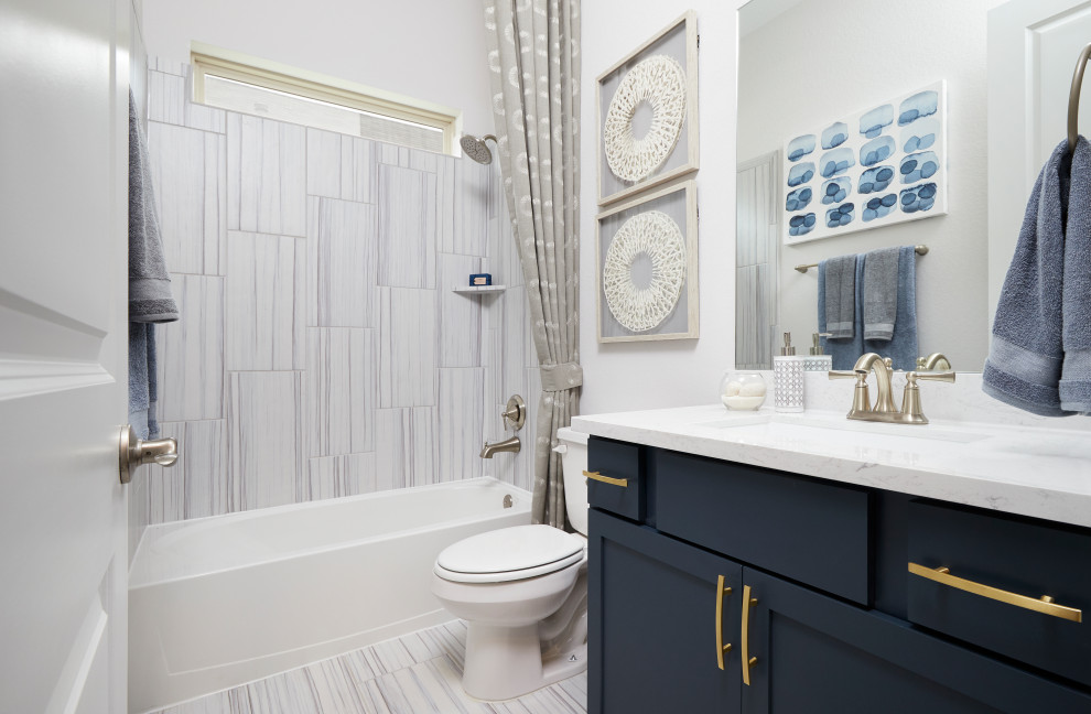Inspiration pour une salle de bain design de taille moyenne pour enfant avec un placard avec porte à panneau encastré, un combiné douche/baignoire, des carreaux de céramique, un mur blanc, un sol en carrelage de céramique, un lavabo encastré, un plan de toilette en marbre, une cabine de douche avec un rideau, un plan de toilette blanc, des portes de placard bleues, un carrelage blanc, un sol blanc et meuble simple vasque.