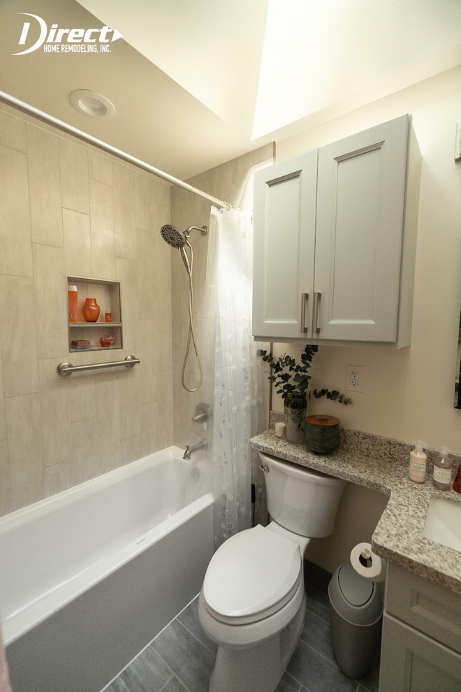 Photo of a medium sized contemporary ensuite bathroom in San Francisco with beaded cabinets, grey cabinets, an alcove bath, a shower/bath combination, a one-piece toilet, beige walls, vinyl flooring, an integrated sink, granite worktops, grey floors, a shower curtain, multi-coloured worktops, beige tiles and ceramic tiles.