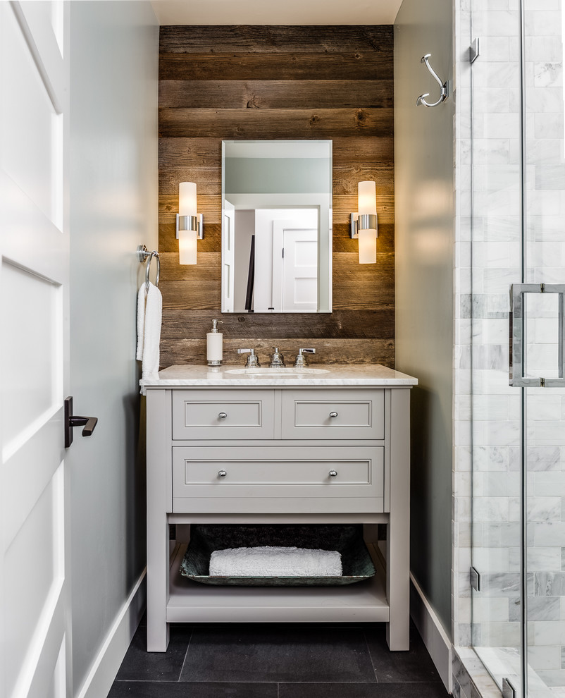 Inspiration pour une petite salle de bain chalet en bois clair avec un placard à porte shaker, une baignoire indépendante, un carrelage gris, un carrelage de pierre, un mur gris, un plan de toilette en marbre, un lavabo encastré, une cabine de douche à porte battante et un sol gris.