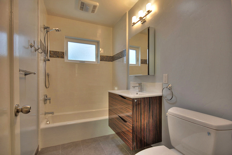 Exemple d'une salle de bain chic en bois brun de taille moyenne avec un placard à porte plane, une baignoire en alcôve, un combiné douche/baignoire, un mur gris, un sol en carrelage de porcelaine, un lavabo intégré, un plan de toilette en quartz modifié et un sol marron.