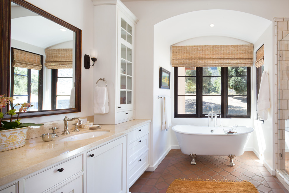 На фото: главная ванная комната в средиземноморском стиле с фасадами с утопленной филенкой, белыми фасадами, отдельно стоящей ванной, белыми стенами и врезной раковиной с