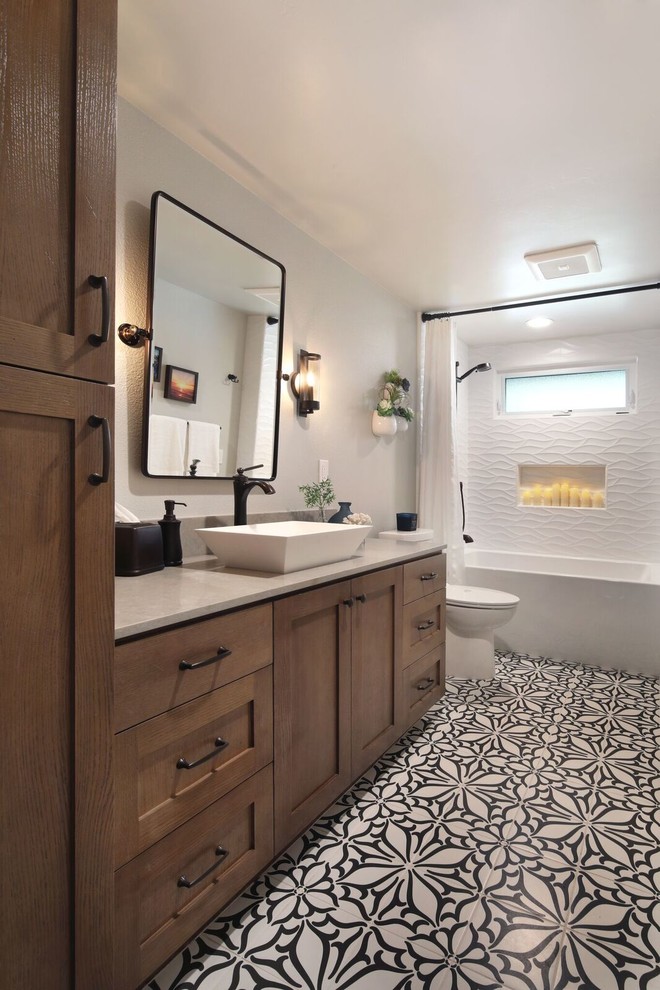 Aménagement d'une salle de bain classique en bois brun de taille moyenne avec un placard avec porte à panneau encastré, une baignoire en alcôve, un combiné douche/baignoire, WC séparés, un carrelage blanc, un mur gris, un sol en carrelage de céramique, une vasque, un plan de toilette en quartz modifié, un sol multicolore, une cabine de douche avec un rideau et un plan de toilette gris.