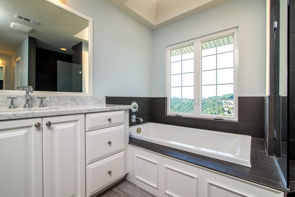 Großes Modernes Badezimmer En Suite mit Einbauwaschbecken, profilierten Schrankfronten, weißen Schränken, Marmor-Waschbecken/Waschtisch, Eckbadewanne, offener Dusche, Toilette mit Aufsatzspülkasten, schwarzen Fliesen, Kieselfliesen und blauer Wandfarbe in San Diego