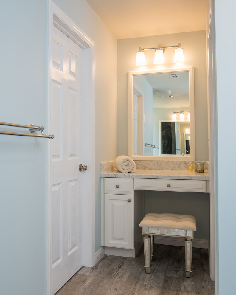 This is an example of a large contemporary ensuite bathroom in San Diego with a built-in sink, raised-panel cabinets, white cabinets, marble worktops, a corner bath, a walk-in shower, a one-piece toilet, black tiles, pebble tiles, blue walls and medium hardwood flooring.