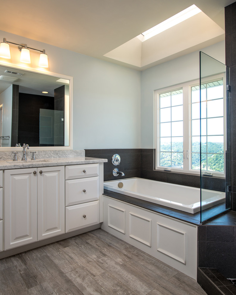 Idéer för att renovera ett stort funkis en-suite badrum, med ett nedsänkt handfat, luckor med upphöjd panel, vita skåp, marmorbänkskiva, ett hörnbadkar, en öppen dusch, en toalettstol med hel cisternkåpa, svart kakel, kakel i småsten och blå väggar