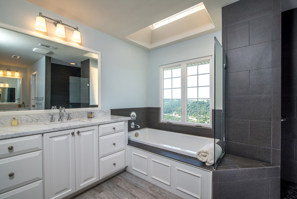 Exemple d'une grande salle de bain principale tendance avec un lavabo posé, un placard avec porte à panneau surélevé, des portes de placard blanches, un plan de toilette en marbre, une baignoire d'angle, une douche ouverte, WC à poser, un carrelage noir, une plaque de galets et un mur bleu.