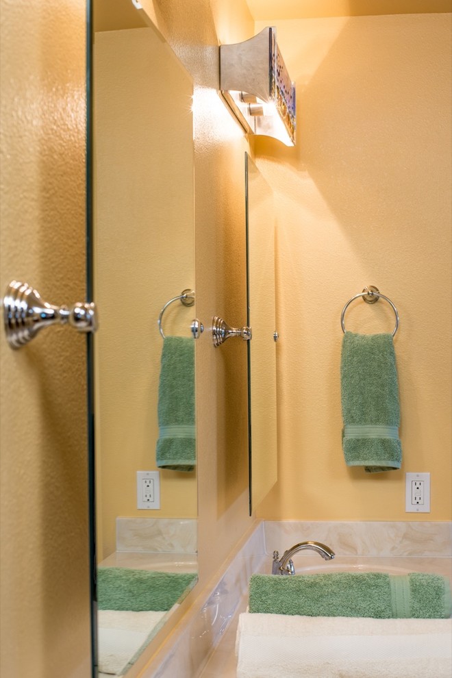 Cette photo montre une grande douche en alcôve principale exotique en bois clair avec un placard à porte plane, une baignoire posée, un carrelage marron, un carrelage en pâte de verre, un mur jaune, un sol en linoléum, un lavabo intégré et un plan de toilette en marbre.