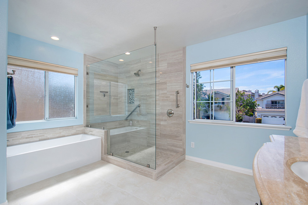 Inspiration for a large coastal ensuite bathroom in San Diego with recessed-panel cabinets, dark wood cabinets, a corner shower, a two-piece toilet, blue tiles, porcelain tiles, blue walls, porcelain flooring, beige floors, an open shower, a corner bath, a submerged sink, engineered stone worktops, beige worktops, a built in vanity unit and double sinks.