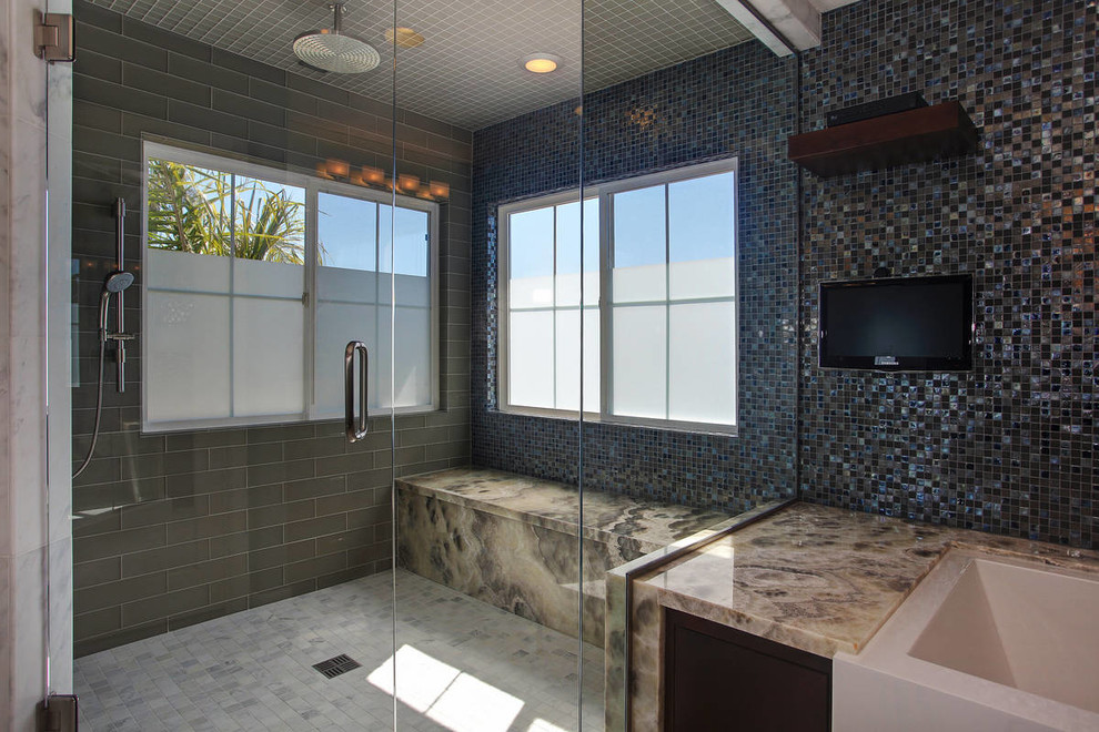 This is an example of a large modern ensuite bathroom in San Diego with a freestanding bath, a corner shower, black tiles, blue tiles, glass tiles, blue walls, marble flooring, white floors and a hinged door.