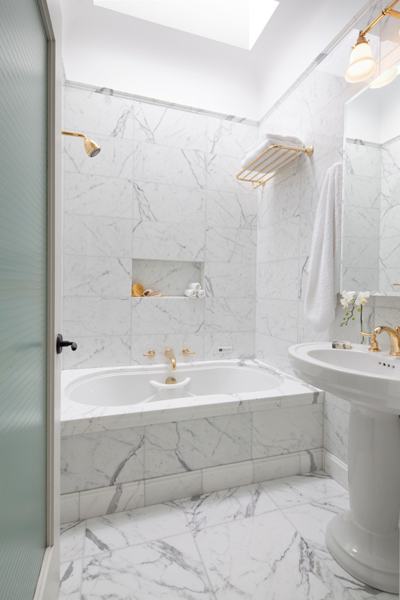 На фото: главная ванная комната среднего размера в классическом стиле с мраморным полом, раковиной с пьедесталом, гидромассажной ванной, душем над ванной, унитазом-моноблоком, белой плиткой, каменной плиткой и белыми стенами с