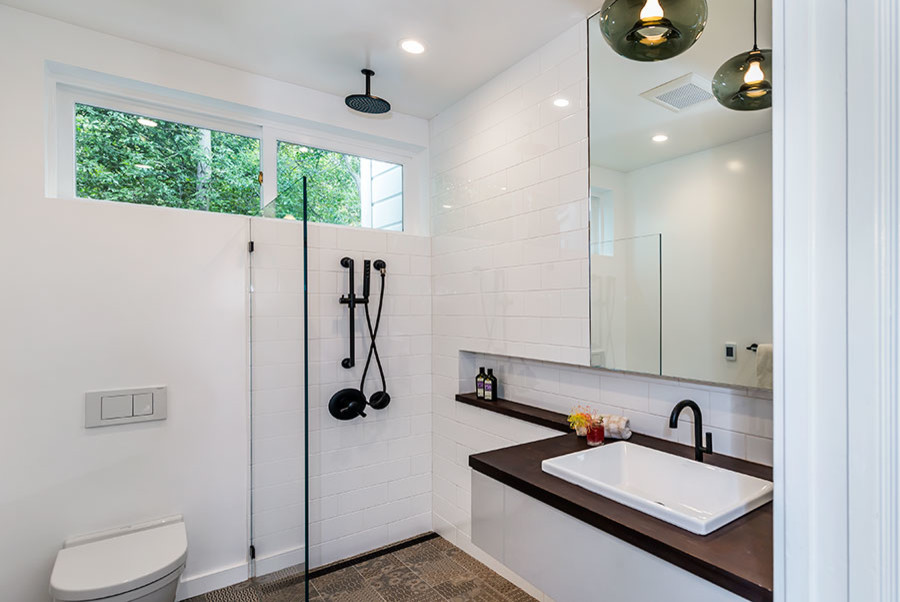 Idéer för ett mellanstort modernt badrum med dusch, med släta luckor, vita skåp, en öppen dusch, en toalettstol med hel cisternkåpa, vit kakel, tunnelbanekakel, vita väggar, klinkergolv i keramik, ett väggmonterat handfat, träbänkskiva, flerfärgat golv och med dusch som är öppen
