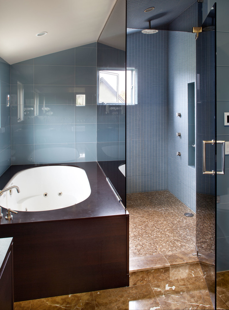 Идея дизайна: огромная баня и сауна в современном стиле с плоскими фасадами, темными деревянными фасадами, столешницей из известняка, полновстраиваемой ванной, синей плиткой, стеклянной плиткой, настольной раковиной, синими стенами и мраморным полом