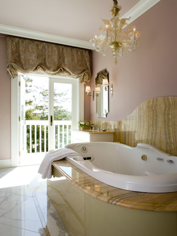 Cette photo montre une grande salle de bain principale chic avec une baignoire posée, un mur rose, un sol en marbre, un plan de toilette en onyx, un carrelage beige et un carrelage de pierre.