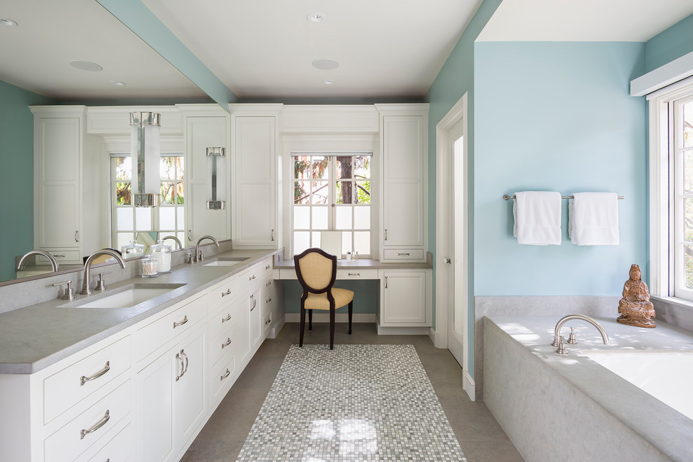 На фото: главная ванная комната среднего размера в стиле неоклассика (современная классика) с фасадами с утопленной филенкой, белыми фасадами, полновстраиваемой ванной, двойным душем, синими стенами, полом из мозаичной плитки, врезной раковиной, бежевой плиткой, плиткой мозаикой и столешницей из известняка