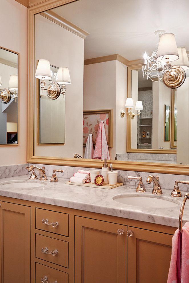 Modelo de cuarto de baño clásico con lavabo suspendido, armarios con paneles empotrados, puertas de armario naranjas, encimera de mármol y paredes beige