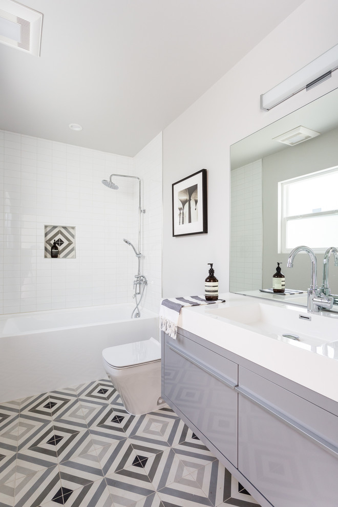 サンフランシスコにあるお手頃価格の中くらいなコンテンポラリースタイルのおしゃれな浴室 (フラットパネル扉のキャビネット、グレーのキャビネット、アルコーブ型浴槽、シャワー付き浴槽	、マルチカラーのタイル、白いタイル、白い壁、一体型シンク、マルチカラーの床、セメントタイル、セメントタイルの床) の写真