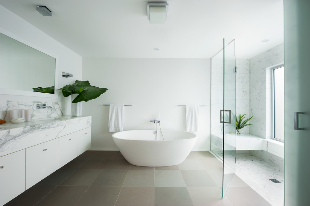 Пример оригинального дизайна: ванная комната в современном стиле с врезной раковиной, плоскими фасадами, белыми фасадами, отдельно стоящей ванной, душем без бортиков и белой плиткой