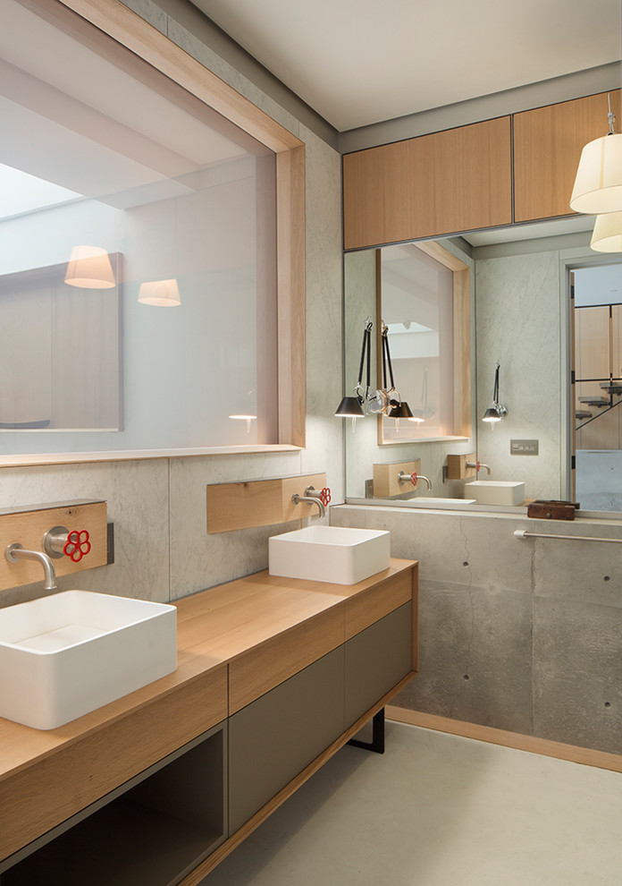 Immagine di una stanza da bagno industriale con ante lisce, pareti grigie, lavabo a bacinella, top in legno, pavimento bianco e top marrone
