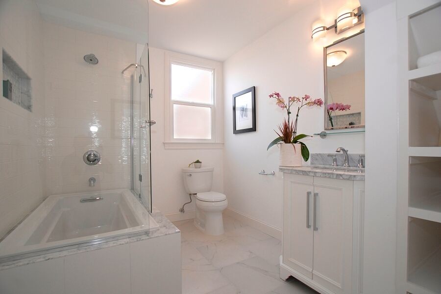 Idée de décoration pour une salle de bain principale tradition de taille moyenne avec un placard à porte affleurante, des portes de placard blanches, une baignoire d'angle, un combiné douche/baignoire, WC séparés, un carrelage blanc, un mur blanc, un sol en marbre, un lavabo encastré, un plan de toilette en marbre, un sol blanc, une cabine de douche à porte battante et un plan de toilette gris.