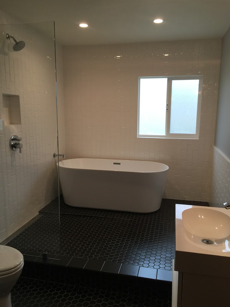 Photo of a large traditional ensuite wet room bathroom in San Francisco with a freestanding bath, white tiles, metro tiles, black floors and an open shower.
