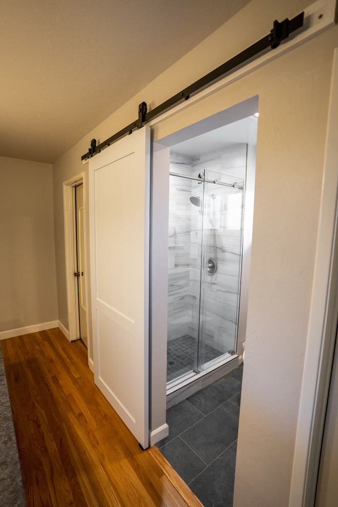 Large modern ensuite bathroom in San Francisco with beaded cabinets, beige cabinets, a one-piece toilet, an integrated sink, granite worktops, black floors, a hinged door, grey worktops, black and white tiles, marble tiles, a double shower, beige walls and cement flooring.