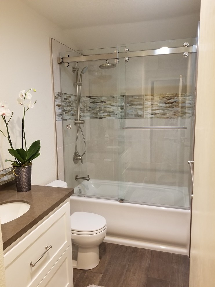 Photo of a small traditional ensuite bathroom in San Francisco with shaker cabinets, white cabinets, an alcove bath, a shower/bath combination, a one-piece toilet, multi-coloured tiles, glass tiles, beige walls, porcelain flooring, a submerged sink, quartz worktops, brown floors, a sliding door and brown worktops.
