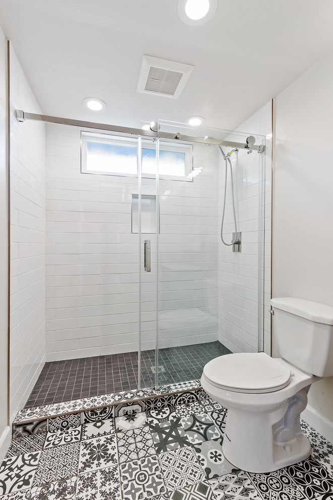 Small modern shower room bathroom in San Francisco with freestanding cabinets, grey cabinets, an alcove shower, a two-piece toilet, white tiles, ceramic tiles, white walls, cement flooring, an integrated sink, quartz worktops, multi-coloured floors, a sliding door and white worktops.