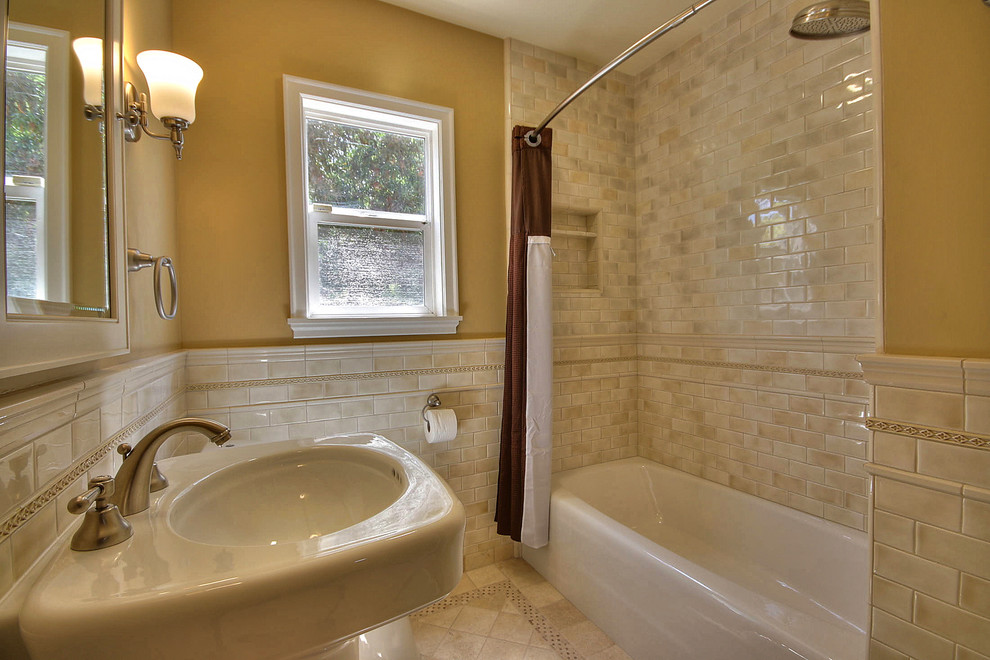 Bild på ett mellanstort vintage badrum, med ett piedestal handfat, ett badkar i en alkov, en dusch/badkar-kombination, en toalettstol med hel cisternkåpa, beige kakel, keramikplattor, gula väggar och klinkergolv i keramik