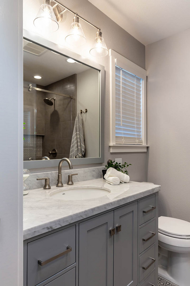 This is an example of a medium sized traditional ensuite bathroom in San Francisco with medium wood cabinets, an alcove shower, a two-piece toilet, grey tiles, ceramic tiles, beige walls, a submerged sink, marble worktops, beige floors, a sliding door, grey worktops and double sinks.