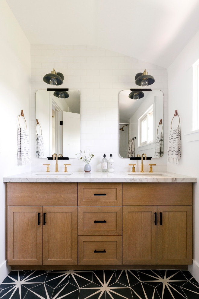 This is an example of a small classic family bathroom in San Francisco with shaker cabinets, white tiles, porcelain tiles, white walls, cement flooring, a submerged sink, white worktops, double sinks, a built in vanity unit, medium wood cabinets, black floors and a vaulted ceiling.