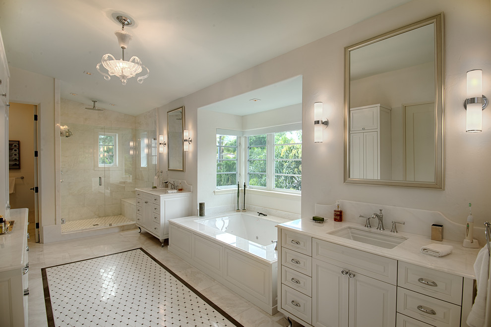 Пример оригинального дизайна: большая главная ванная комната в классическом стиле с врезной раковиной, белыми фасадами, мраморной столешницей, полновстраиваемой ванной, душем в нише, белой плиткой, каменной плиткой, белыми стенами, мраморным полом, фасадами с выступающей филенкой, белым полом и белой столешницей