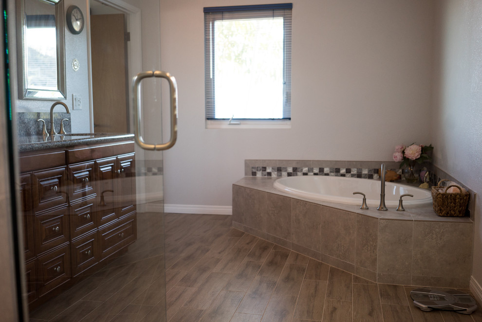 Photo of a medium sized classic ensuite bathroom in San Diego with recessed-panel cabinets, medium wood cabinets, a corner bath, an alcove shower, a two-piece toilet, beige tiles, ceramic tiles, white walls, ceramic flooring, a built-in sink and granite worktops.