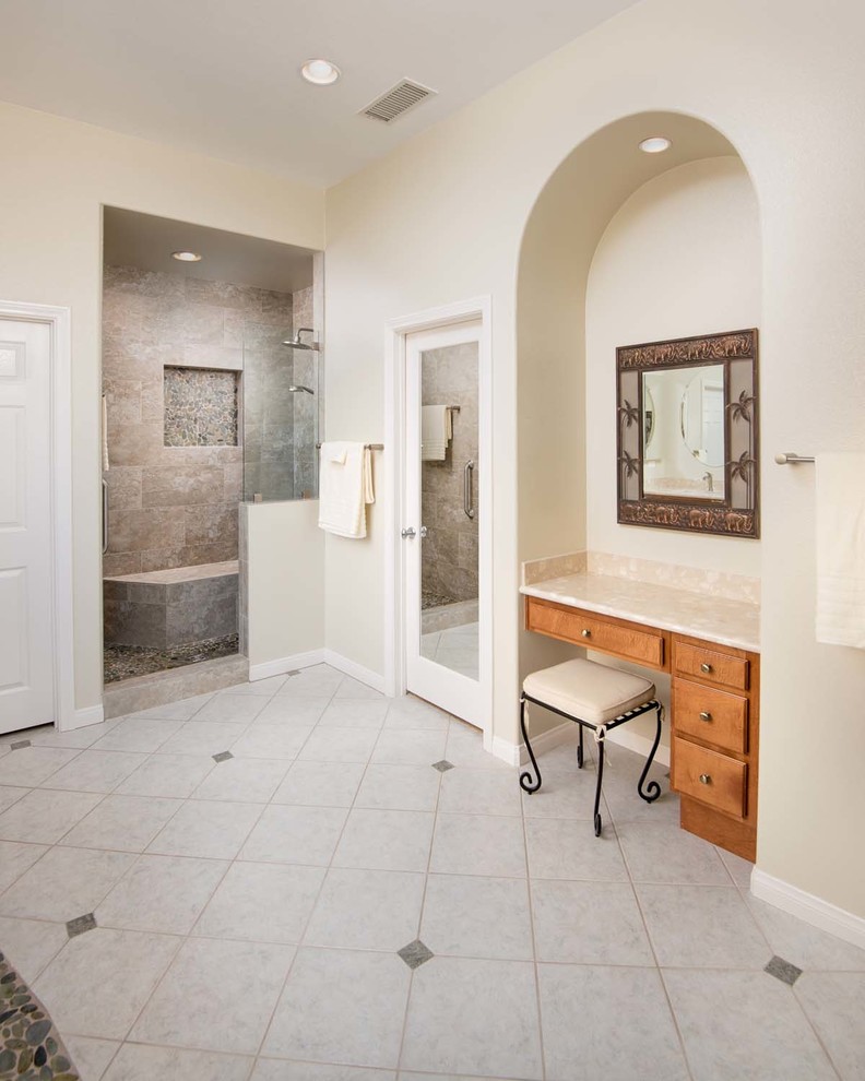 This is an example of a large traditional ensuite bathroom in San Diego with a submerged sink, raised-panel cabinets, medium wood cabinets, engineered stone worktops, a built-in bath, a walk-in shower, a one-piece toilet, beige tiles, porcelain tiles, beige walls and porcelain flooring.
