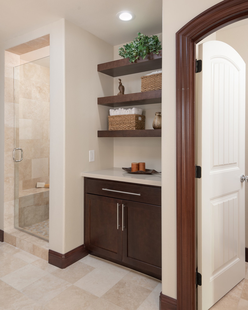 This is an example of an expansive modern ensuite bathroom in San Diego with recessed-panel cabinets, dark wood cabinets, a freestanding bath, an alcove shower, a two-piece toilet, beige tiles, ceramic tiles, beige walls, travertine flooring, a built-in sink and engineered stone worktops.