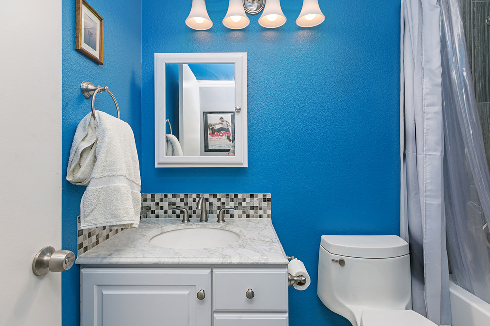 Réalisation d'une salle de bain tradition de taille moyenne avec un placard avec porte à panneau encastré, des portes de placard blanches, WC séparés, un carrelage gris, des carreaux de porcelaine, un mur bleu, un sol en carrelage de porcelaine, un lavabo posé, un plan de toilette en quartz, un sol gris et une cabine de douche à porte coulissante.