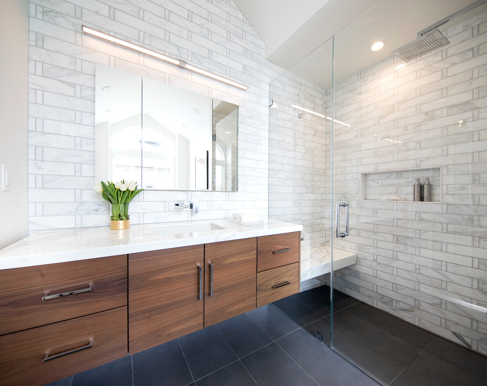 Example of a trendy 3/4 gray tile black floor alcove shower design in San Francisco with flat-panel cabinets, dark wood cabinets, beige walls, an undermount sink, a hinged shower door and white countertops