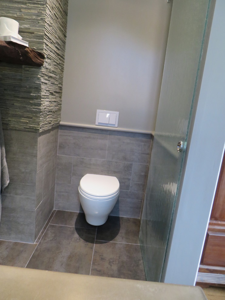 Ispirazione per una stanza da bagno padronale contemporanea di medie dimensioni con lavabo integrato, ante lisce, top in cemento e WC sospeso