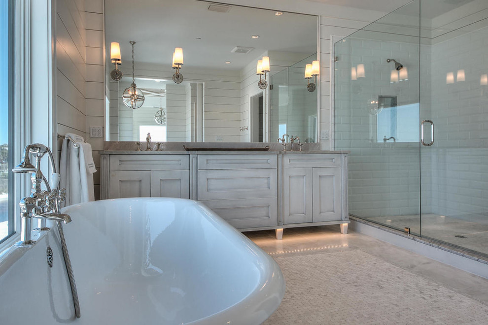 Inspiration for a medium sized nautical ensuite bathroom in Miami with freestanding cabinets, distressed cabinets, a freestanding bath, a double shower, white tiles, stone tiles, white walls, marble flooring, a console sink and marble worktops.